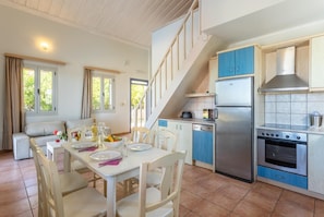 Una cocina moderna con horno empotrado, refrigerador y comedor con mesa dispuesta para dos.