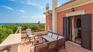 Ein Balkon mit einer Couch, Stühlen und einem Tisch, mit Blick auf eine schöne Aussicht.