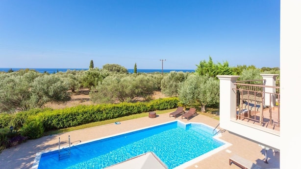 Une piscine avec vue sur la mer et les oliviers.