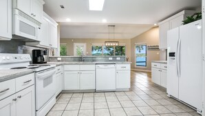 A modern kitchen with white cabinets, a built-in microwave, a stove, and a dishwasher.