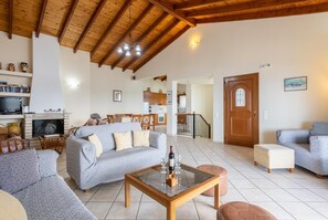 A spacious living room with a fireplace, a dining area, and a kitchen in the background. - Villa Kerkyroula - Three Bedroom Villa, Sleeps 7 (Katavolos)