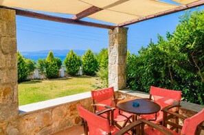 An outdoor patio with a table and chairs, stone walls, and a view of the sea and mountains. - Villa Katerina Private Pool, Sea Views, A/C, WiFi (Skopelos)