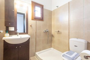 Un baño con lavabo, espejo, ducha, inodoro y toalla.