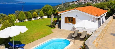 Une propriété résidentielle dotée d’une piscine, d’un espace extérieur aménagé et offrant une vue sur la mer et les collines.