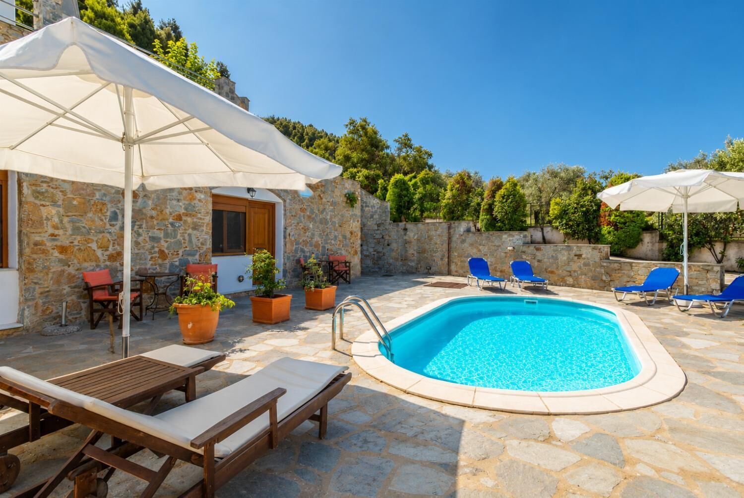 A pool area with lounge chairs, a table, and umbrellas.