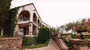 A building with a stone facade, arched windows, and a balcony with wrought iron railings. - Posada la Ermita (San Miguel de Allende)
