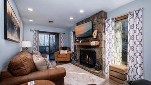 Una sala de estar con chimenea, sofá, sillón y una mesa de centro.