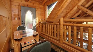 Une cabane en bois dotée d’un coin repas avec une table et des chaises, d’une fenêtre offrant une vue agréable et d’une rambarde en bois.