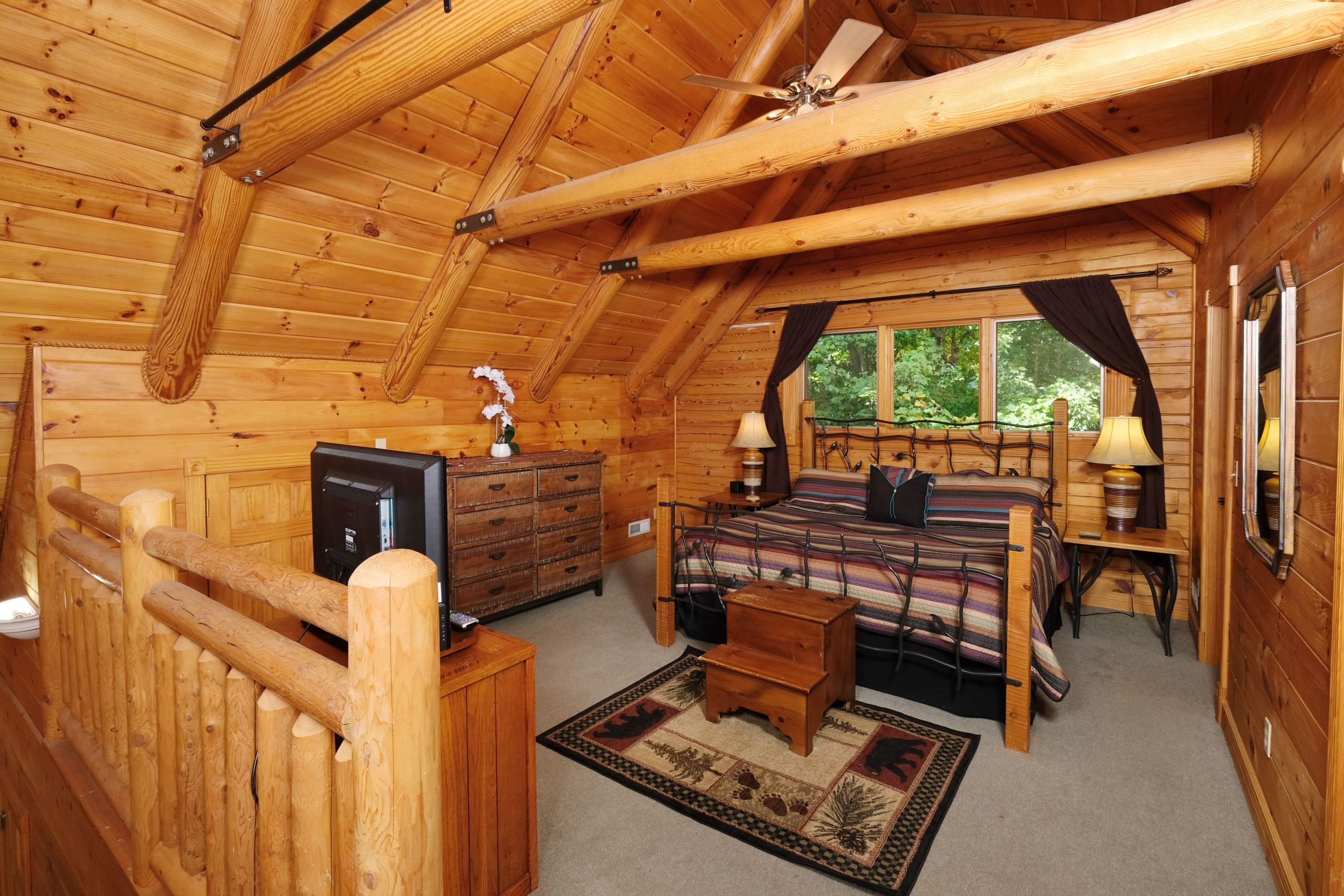 Ein gemütliches Schlafzimmer in einer Blockhütte mit Bett, Schminktisch und Schreibtisch.