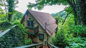 A rustic cabin with a wooden exterior, a balcony, and a staircase leading to the entrance.