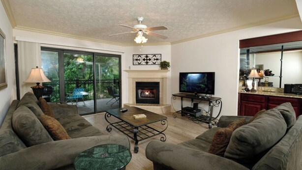A living room with a fireplace, a television, and a dining area with a kitchen in the background. - Creek View GH403 - Sip coffee on the balcony with the sound of the creek! (Gatlinburg)