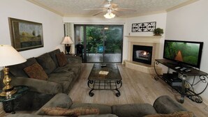 A living room with a sofa set, a coffee table, a fireplace, a television, and a ceiling fan. - Creek View GH403 - Sip coffee on the balcony with the sound of the creek! (Gatlinburg)