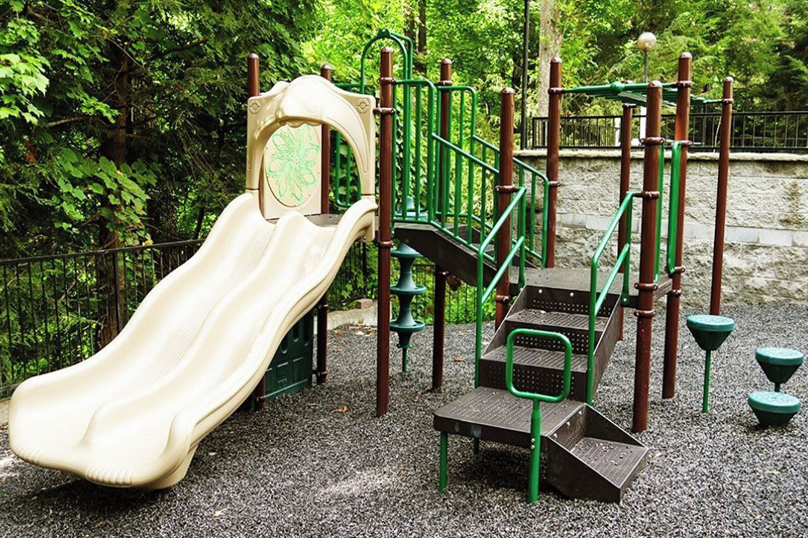 Un parque infantil con un tobogán, escaleras de acceso y un pequeño puente.