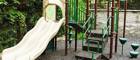 Un parque infantil con un tobogán, escaleras de acceso y un pequeño puente.