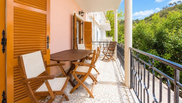 Un balcone con tavolo e sedie, vista su una rigogliosa collina verde.