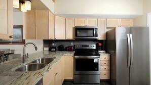 A modern kitchen with granite countertops, stainless steel appliances, and wooden cabinets. - Three Bears and a Mountain HA302 - Community - Fireplace - Mountain Views (Gatlinburg)