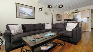 A living room with a sectional sofa, a coffee table, and a kitchen in the background. - Three Bears and a Mountain HA302 - Community - Fireplace - Mountain Views (Gatlinburg)