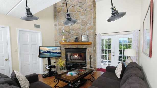 A cozy living room with a stone fireplace, a television, and a comfortable seating area. - Three Bears and a Mountain HA302 - Community - Fireplace - Mountain Views (Gatlinburg)