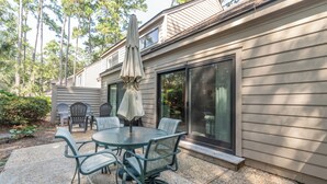A patio with a round table and chairs, a covered umbrella, and a sliding glass door.