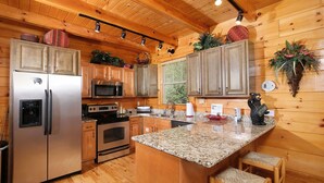 A wooden cabin kitchen with a central island, built-in appliances, and rustic decor. - Hemlock Ridge 1713 - Mountain View from Hot Tub (Gatlinburg)