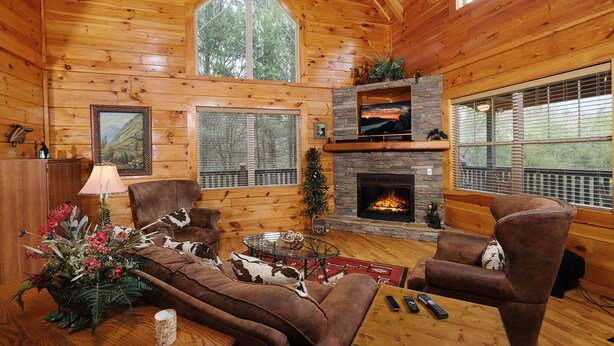 A cozy log cabin interior with a fireplace, leather furniture, and a large window. - Hemlock Ridge 1713 - Mountain View from Hot Tub (Gatlinburg)