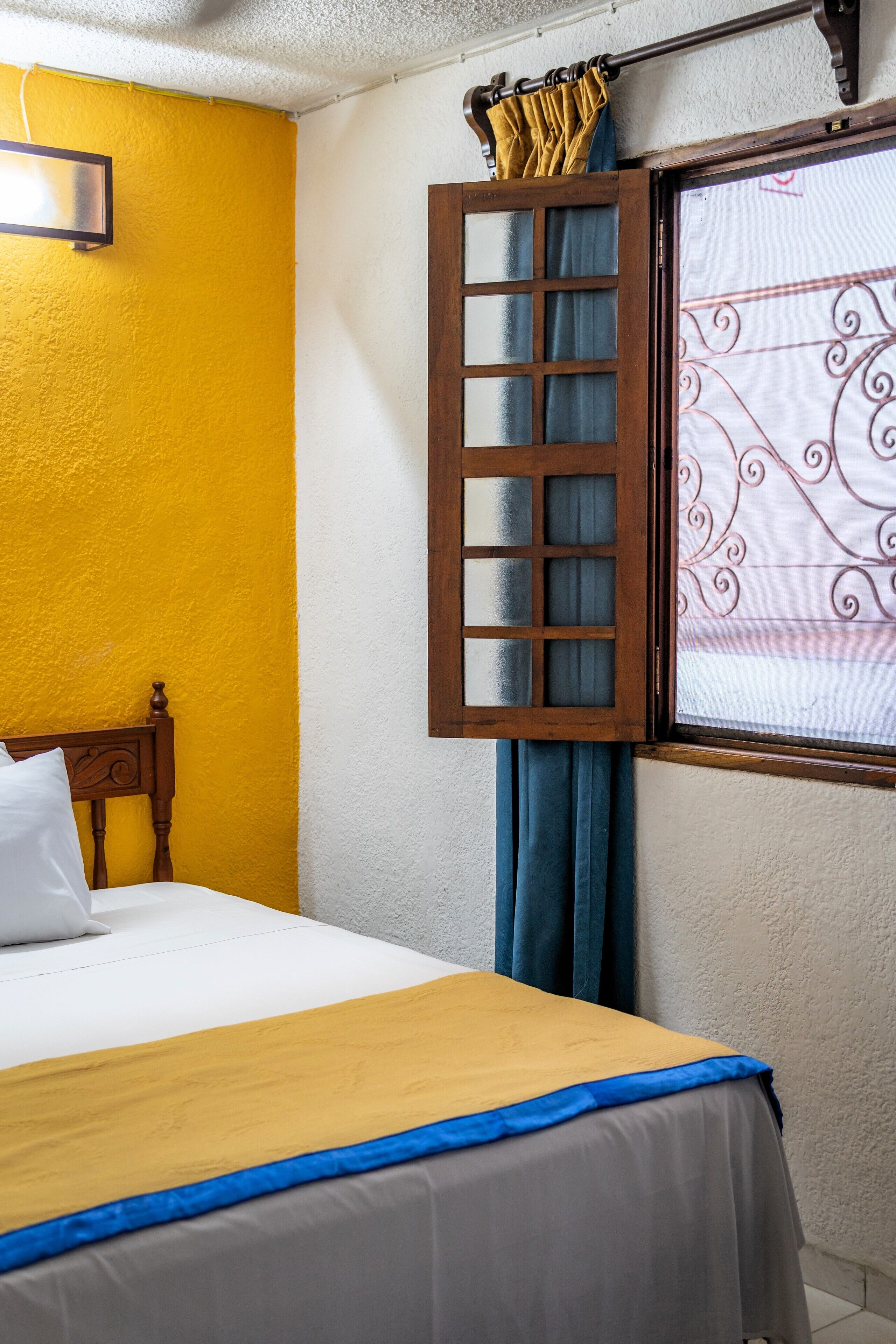 A room with a bed, a window with curtains, and a wall-mounted TV.