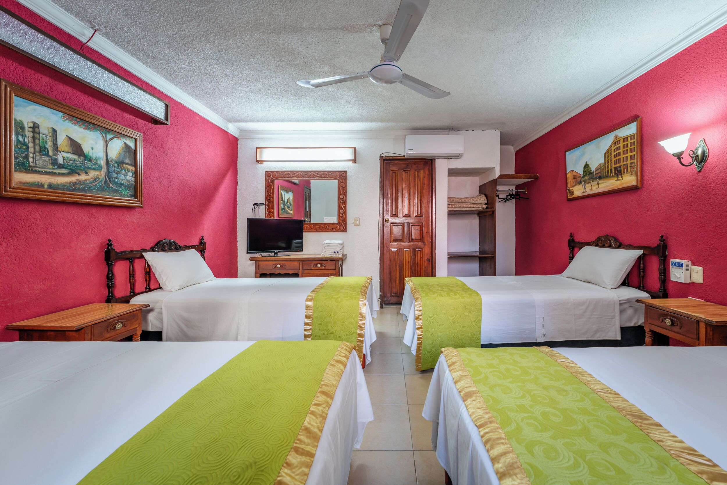 Habitación de hotel con dos camas, televisión, espejo y puerta.
