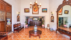 A spacious lobby with a round wooden table, ornate wooden furniture, a chandelier, and a large mirror. - Hotel Santa Lucía (Mérida)