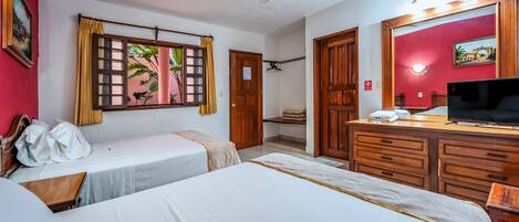 A hotel room with two single beds, a wooden dresser, a television, and a ceiling fan.