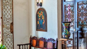 A traditional interior with a wooden bench, a glass table, and a decorative vase. - Hotel Santa Lucía (Mérida)