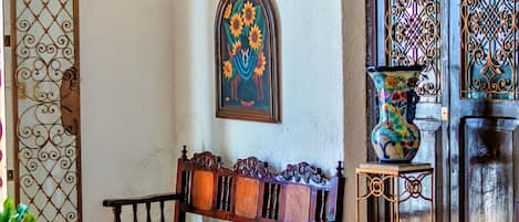 Un interior tradicional con un banco de madera, una mesa de vidrio y un jarrón decorativo.