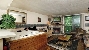 Un salón acogedor con chimenea de piedra, un ventanal grande y un sofá cómodo.