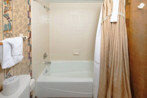 A bathroom with a bathtub, toilet, and a towel rack.