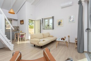 A spacious living area with a sofa, a dining table, and a kitchen in the background.