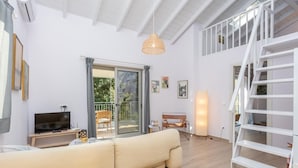 Un salon spacieux avec un canapé, un téléviseur et un balcon.