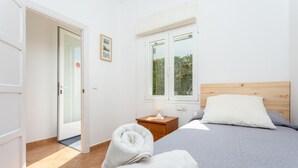 A bedroom with a bed, a nightstand, a window, and a door. - Villa Torreta - Three Bedroom Villa, Sleeps 4 (Punta Prima)