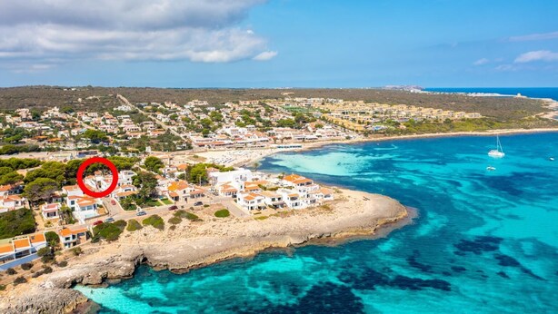 A coastal town with buildings along the shore, a clear blue sea, and a sailboat in the distance. - Villa Torreta - Three Bedroom Villa, Sleeps 4 (Punta Prima)