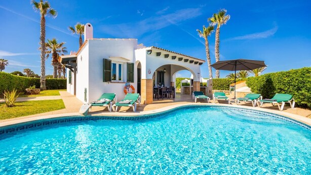 Una piscina con sillas de descanso, un espacio de patio y palmeras.