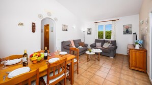 Una sala de estar con comedor, un conjunto de sofás y una mesita con un florero.