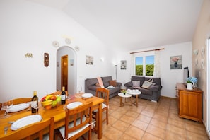 Een woonkamer met een eethoek, een zithoek en een kleine tafel met een bloevas.