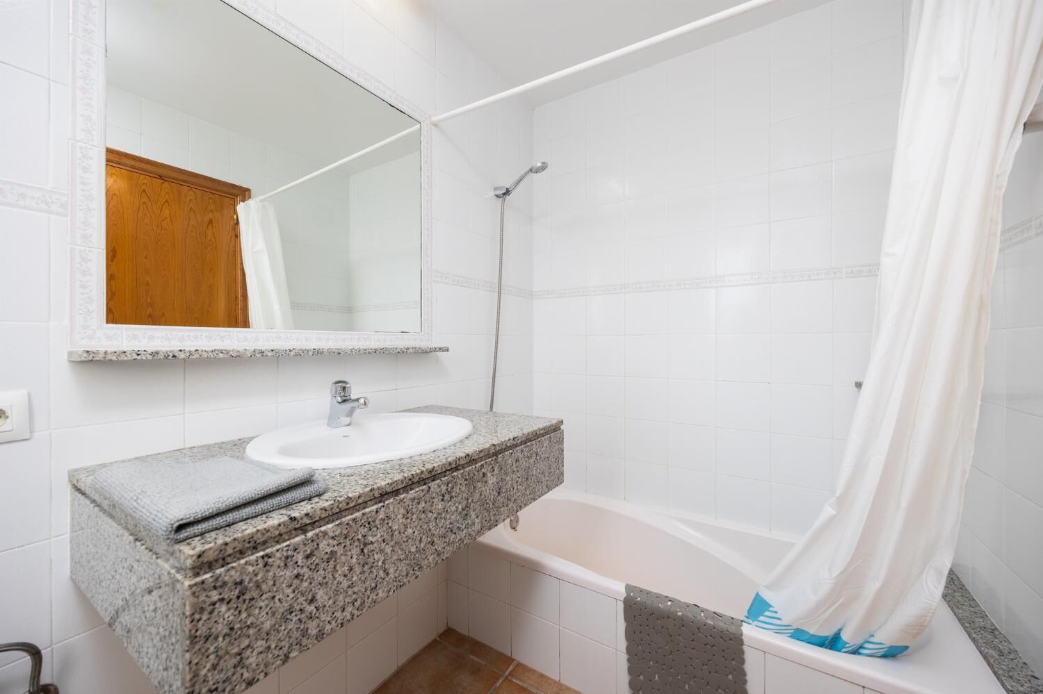 A bathroom with a granite countertop sink, a mirror, a shower, and a bathtub.