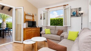 Una sala de estar con un sofá, un televisor, una mesita y vistas al exterior.