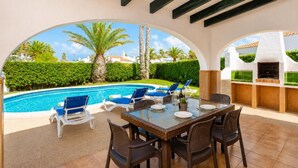 Un patio exterior con piscina, sillas de descanso y una mesa de comedor.