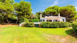 A two-story house with a well-maintained lawn and a stone wall. - Villa Binibety - Three Bedroom Villa, Sleeps 6 (Binibeca)