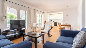 A modern living room with a TV, sofa, and dining area. - Villa Binibety - Three Bedroom Villa, Sleeps 6 (Binibeca)