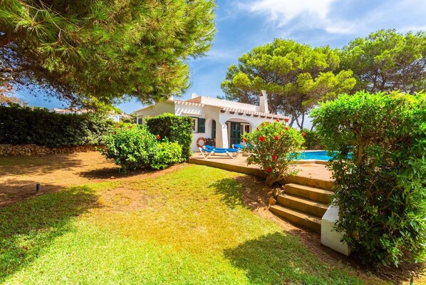 Eine Villa mit Swimmingpool, umgeben von üppigem Grün und einem gepflegten Rasen.