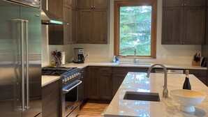 Una cocina moderna con electrodomésticos de acero inoxidable, armarios de madera oscura y una isla grande con fregadero.