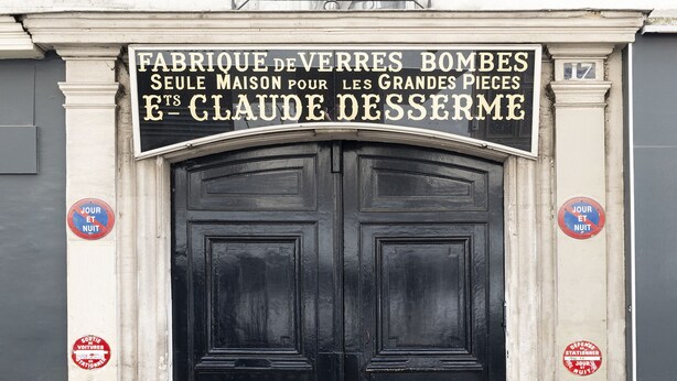 Une porte noire à deux battants, avec une enseigne au-dessus.