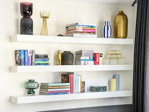 A bookshelf with books, decorative items, and a vase. - LivinParis | Luxury AC 3 Bedrooms Le Marais III (Paris)