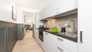 Une cuisine moderne avec des armoires blanches, un plan de travail noir et des appareils en acier inoxydable.
